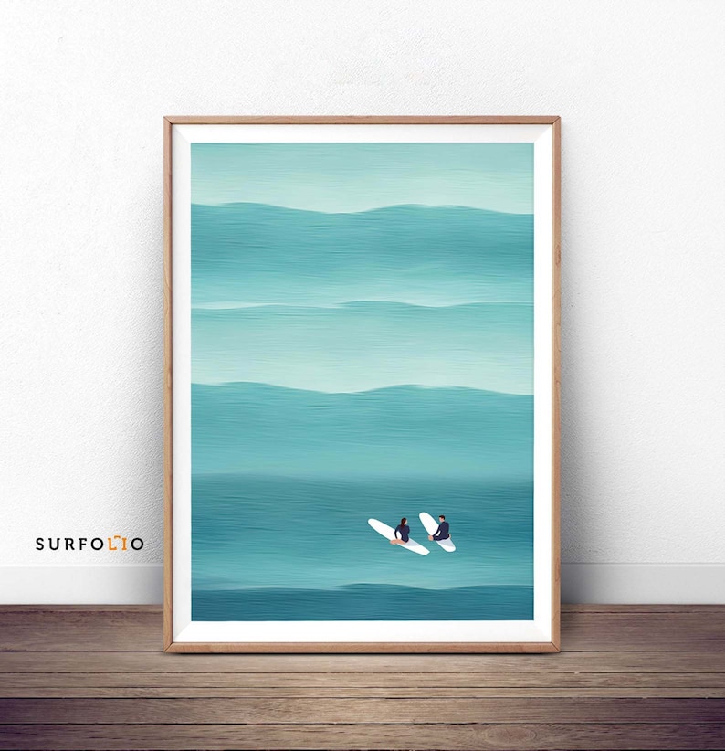 May include: A framed print of a minimalist painting depicting two figures on surfboards in a turquoise ocean with white waves.