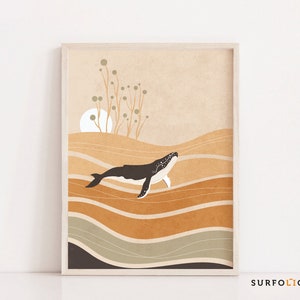 May include: A framed art print featuring a stylized illustration of a whale swimming above layered, abstract waves. The color palette includes shades of brown, beige, and gray. The whale is dark with white accents. The artwork has a minimalist, nature-inspired theme.