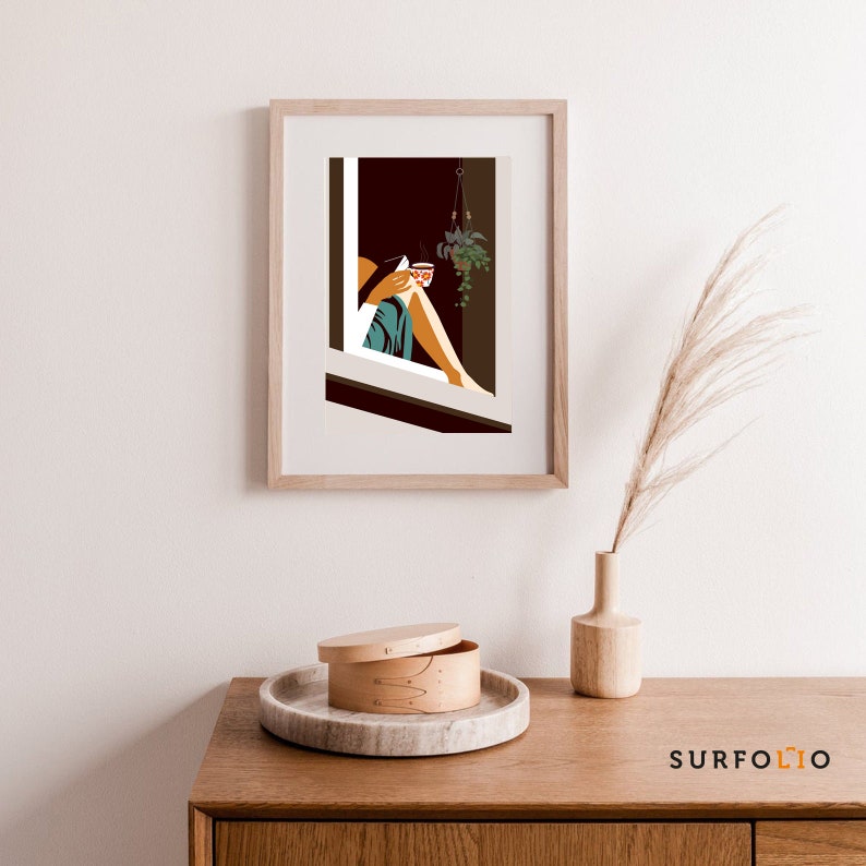 Op de afbeelding: Een ingelijste illustratie van een persoon die in een raam zit met een kopje koffie en een hangende plant. Het raam is omlijst met hout en de illustratie is in een minimalistische stijl.