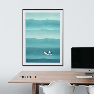 May include: A framed abstract painting of two surfers on white surfboards in a teal ocean with white waves. The painting is in a black frame and is hanging on a white wall.