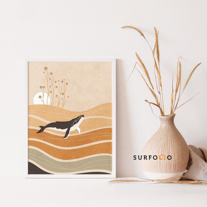May include: A framed art print featuring a whale swimming in the ocean. The artwork has a minimalist style with a color palette of brown, beige, and white. The print is displayed on a white surface, with a vase of dried plants to the right.