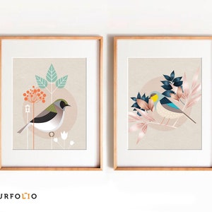 May include: Two framed prints with a minimalist design featuring birds and foliage. The print on the left features a green and white bird with a red berry branch. The print on the right features a blue and yellow bird with pink and blue foliage.