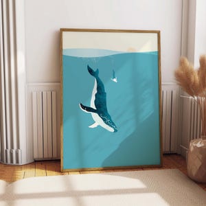 Puede incluir: Un cuadro rectangular vertical enmarcado en madera que muestra una ballena azul oscuro nadando en agua turquesa. Una pequeña figura blanca de una persona nada cerca de la superficie bajo un sol pálido. La obra utiliza colores planos y formas simples.