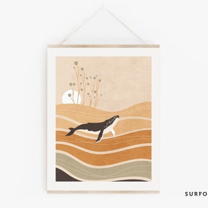 May include: A framed art print featuring a whale swimming in a stylized ocean. The artwork uses a palette of warm earth tones, with a black and white whale against a backdrop of layered brown and tan waves. The print is displayed with a wooden frame.