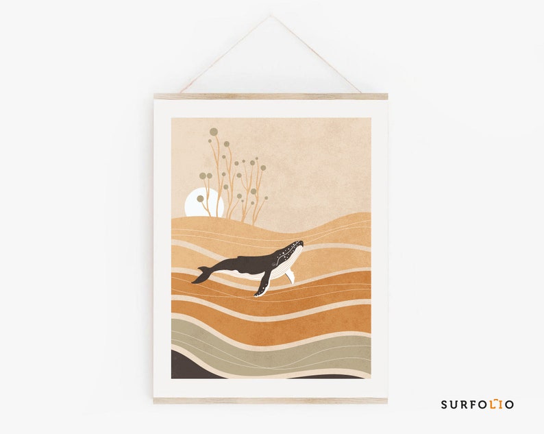 May include: A framed art print featuring a whale swimming in a stylized ocean. The artwork uses a palette of warm earth tones, with a black and white whale against a backdrop of layered brown and tan waves. The print is displayed with a wooden frame.