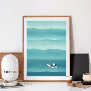May include: A framed illustration of two people on surfboards in a turquoise ocean with white waves. The ocean is painted with horizontal brushstrokes.