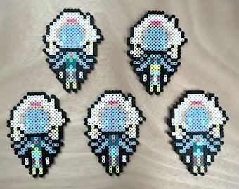 May include: Five handmade perler bead keychains featuring a blue and white character with a crown. The character is surrounded by a white halo and has a yellow and purple design on its clothing.