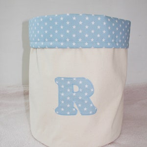 May include: A white canvas storage bin with a blue star patterned fabric top and a blue star patterned letter "R" on the front.