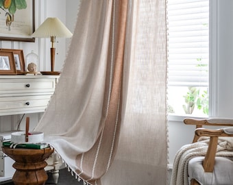 May include: A pair of sheer beige linen curtains with a brown stripe and tassel trim. The curtains are hanging in a window with white blinds.