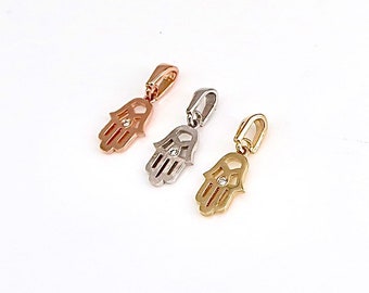 May include: Three hamsa hand charms with a single diamond in the center of each charm. The charms are in gold, silver, and rose gold.