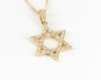 May include: A gold chain necklace with a pendant in the shape of a Star of David. The pendant is covered in small, clear stones.