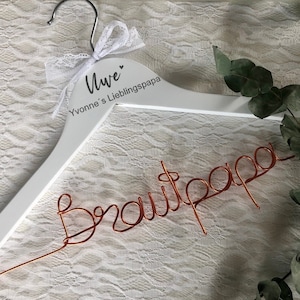 Könnte beinhalten: Ein weißer Holz Kleiderbügel mit dem Text "Liebe Yvonne's Lieblingspapa" und einer Aufschrift aus Kupferdraht, die "Brautpapa" lautet.