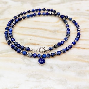 Op de afbeelding: Een dubbele ketting van blauwe lapis lazuli kralen met een zilveren sluiting en een kleine blauwe lapis lazuli hanger.