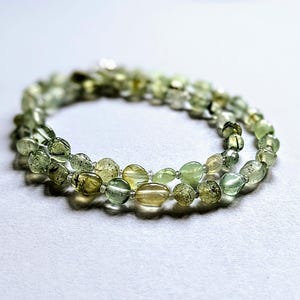 May include: A double strand necklace made of green and brown oval-shaped beads.