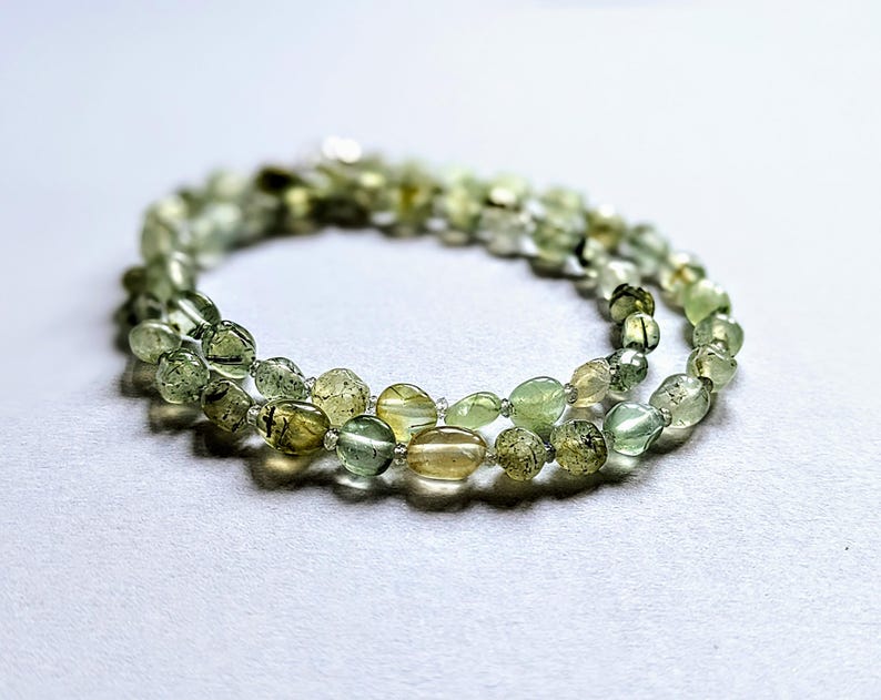 May include: A double strand necklace made of green and brown oval-shaped beads.