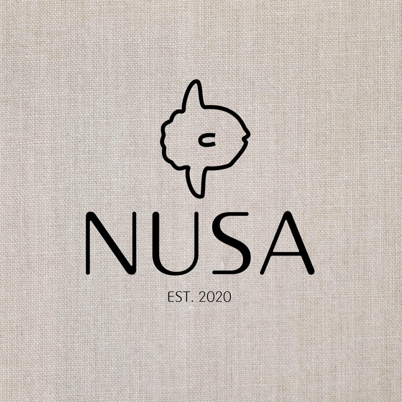 May include: A logo featuring a black outline of a sunfish above the word "NUSA" in a bold, sans-serif font. Below the word "NUSA" is the text "EST. 2020". The background is a textured, off-white fabric.