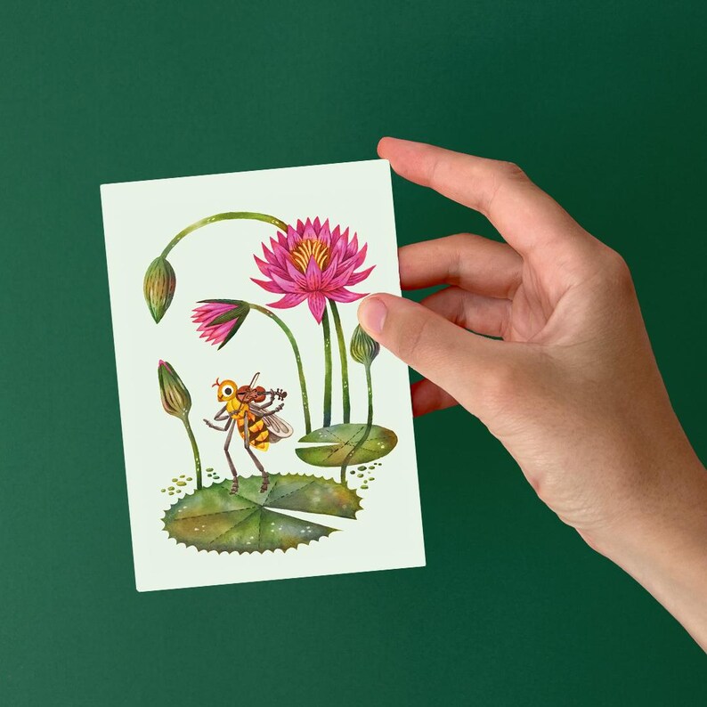 May include: A watercolor illustration of a pink water lily with a yellow center and a bee with brown and yellow stripes sitting on a green lily pad.