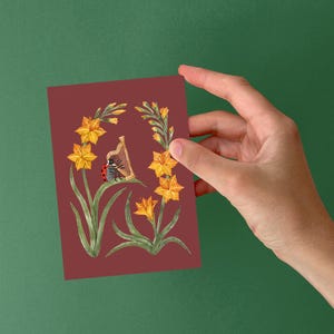 K&ouml;nnte beinhalten: Ein roter Marienk&auml;fer spielt auf einer Harfe, umgeben von gelben Blumen auf einem burgunderroten Hintergrund.