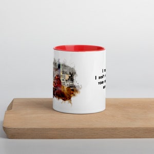 May include: White ceramic coffee mug with a red rim. The mug features a watercolor-style image of a person sitting at a table with a quote that reads "I don't need your kind of love, but I'll take your money".