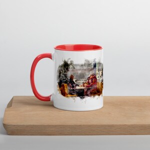 May include: A white ceramic mug with a red rim and handle. The mug features a watercolor illustration of two people sitting at a table in a diner.