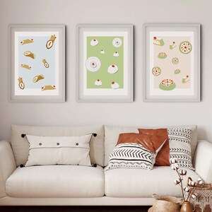 Può includere: Tre stampe incorniciate con diversi design di pasticceria. La prima stampa presenta uno sfondo blu chiaro con un motivo di pasticcini marroni e bianchi. La seconda stampa presenta uno sfondo verde chiaro con un motivo di pasticcini bianchi e rossi. La terza stampa presenta uno sfondo rosa chiaro con un motivo di pasticcini bianchi e rossi.