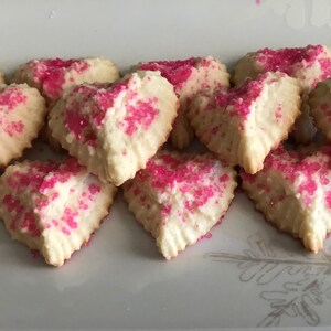 May include: A plate of heart-shaped sugar cookies decorated with pink sprinkles.