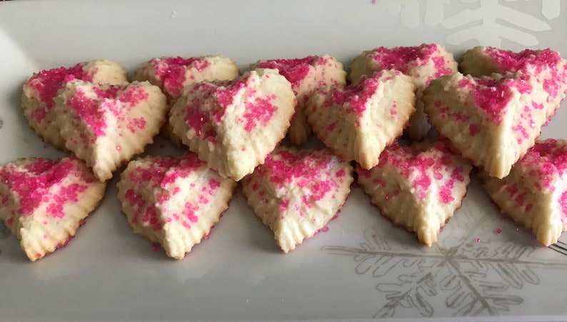 May include: A plate of heart-shaped sugar cookies decorated with pink sprinkles.