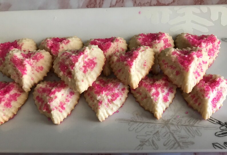 May include: A plate of heart-shaped sugar cookies decorated with pink sprinkles.