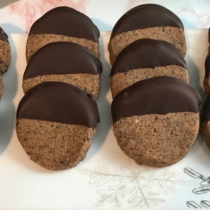 May include: A plate of round, chocolate-covered cookies. The cookies are a light brown color and have a smooth, dark chocolate topping.