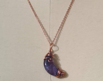 May include: A copper chain necklace with a crescent moon pendant made of amethyst wrapped in copper wire.
