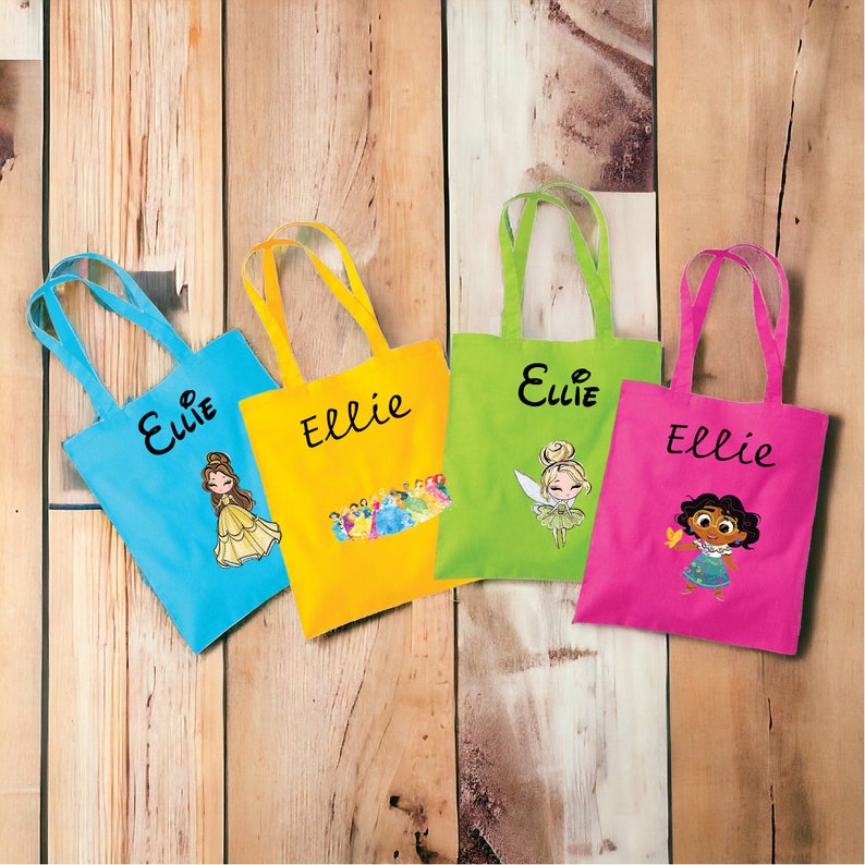 May include: Four colourful tote bags with the name "Ellie" printed on each bag. Each bag features a different princess character: Belle, a group of princesses, Tinkerbell, and a princess from a different culture.
