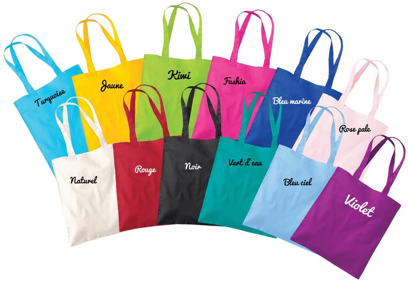 May include: A collection of 12 colourful tote bags with different embroidered text in French. The bags are arranged in a semi-circle, with the handles facing outwards. The colours of the bags include turquoise, yellow, green, fuchsia, blue, pink, red, black, white, teal, light blue, and purple.