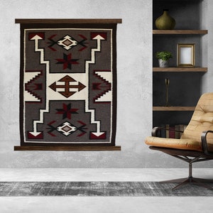 May include: A gray, red, and white Native American rug with geometric patterns hangs on a wall above a gray rug. A brown leather armchair sits in front of the rug.