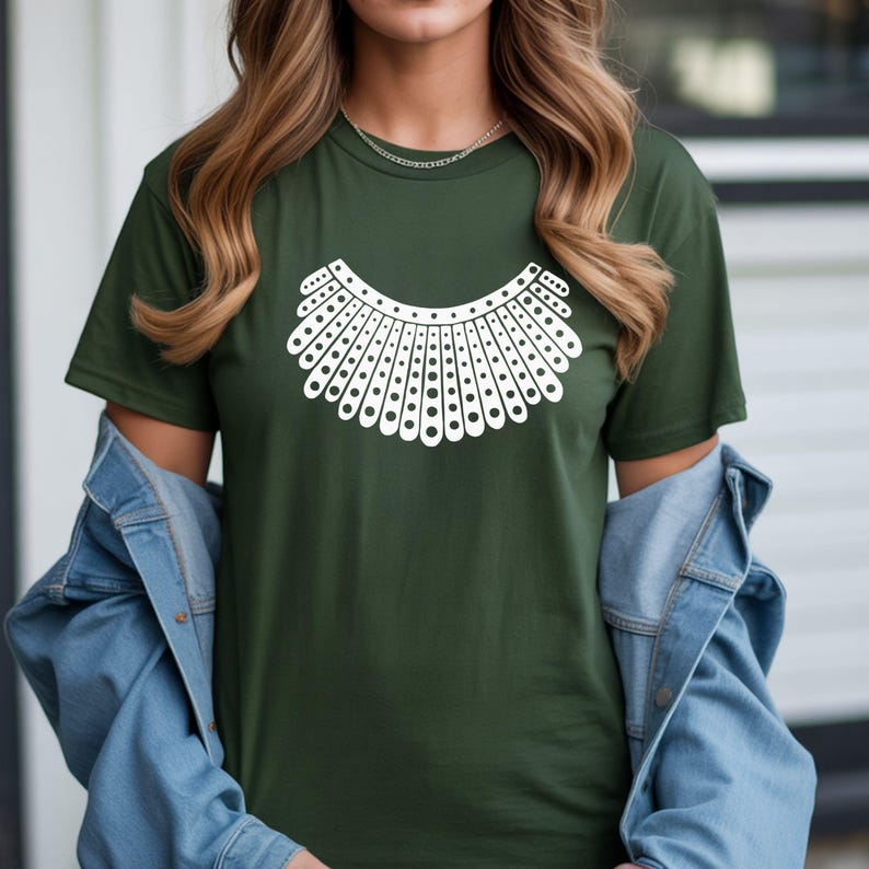 A woman wearing a green t-shirt with a white graphic design on it, standing in front of a building.