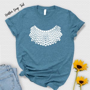a blue t-shirt with a white graphic design, a pair of jeans, and two yellow sunflowers.
