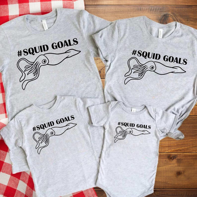 a collection of four gray t-shirts with the text "# SQUID GOALS" printed on them.