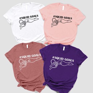 four t-shirts with the same design, featuring a squid graphic and the text "#SQUID GOALS" printed on them.