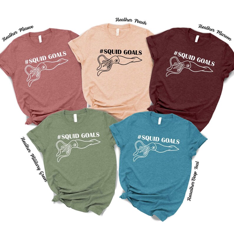 a collection of five t-shirts, each with a unique color and design, featuring the text "# SQUID GOALS" printed on them.