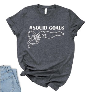 A gray t-shirt with a white graphic of an octopus and the text "#SQUID GOALS" printed on it.