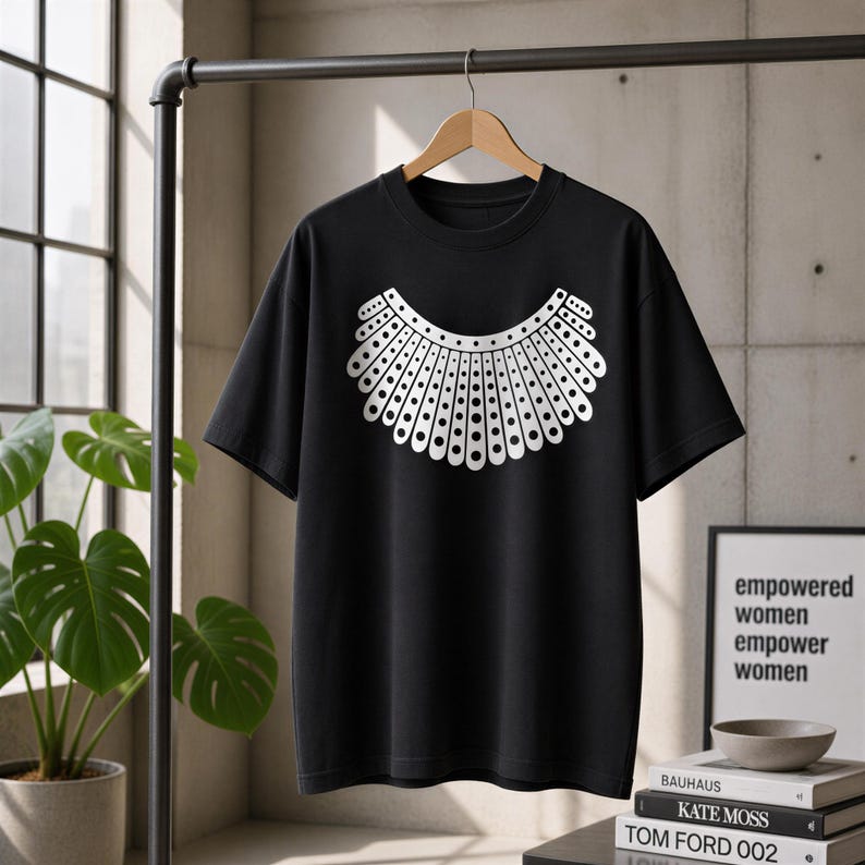 A black t-shirt with a white design of a rooster's head is hanging on a clothing rack in a room with a potted plant and books.