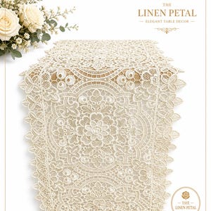 May include: Cream-colored lace table runner with floral and geometric patterns. The runner features intricate detailing and a scalloped edge. The text "THE LINEN PETAL - ELEGANT TABLE DECOR" is displayed in the image. A bouquet of white roses is in the upper left corner.