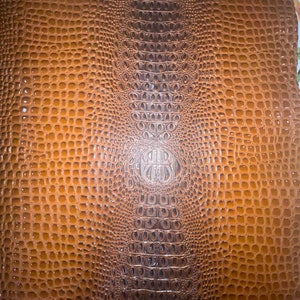 May include: Brown faux crocodile leather with a textured pattern.