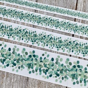 May include: White ribbon with a repeating pattern of green eucalyptus leaves and branches. The ribbon is ribbed and has a delicate, natural aesthetic, perfect for crafting or gift wrapping.