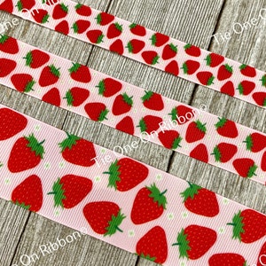 Puede incluir: Cinta rosa con un patrón repetido de fresas rojas. La cinta está sobre una superficie de madera.