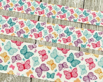 May include: White ribbon with a repeating pattern of colourful butterflies. The butterflies are in shades of pink, purple, blue, teal, and yellow.