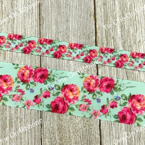 Puede incluir: Primer plano de una cinta azul claro con estampado floral con rosas rosas y naranjas. La cinta est&aacute; sobre una superficie de madera.