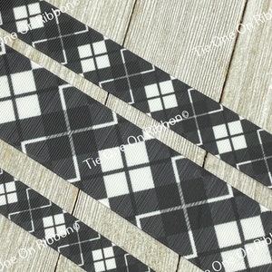 May include: Black and white plaid ribbon with a diamond pattern. The ribbon is on a wooden surface.