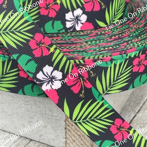 May include: Black and green ribbon with a tropical print featuring pink and white hibiscus flowers and green palm leaves. The ribbon is rolled up and the text "Tie One On Ribbon" is visible on the ribbon.