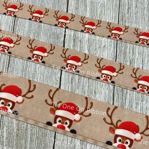 May include: Beige ribbon with a repeating pattern of red-nosed reindeer wearing Santa hats. The reindeer are looking out from behind the ribbon.