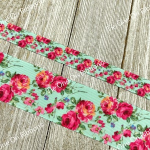 Puede incluir: Primer plano de una cinta azul claro con estampado floral con rosas rosas y naranjas. La cinta est&aacute; sobre una superficie de madera.